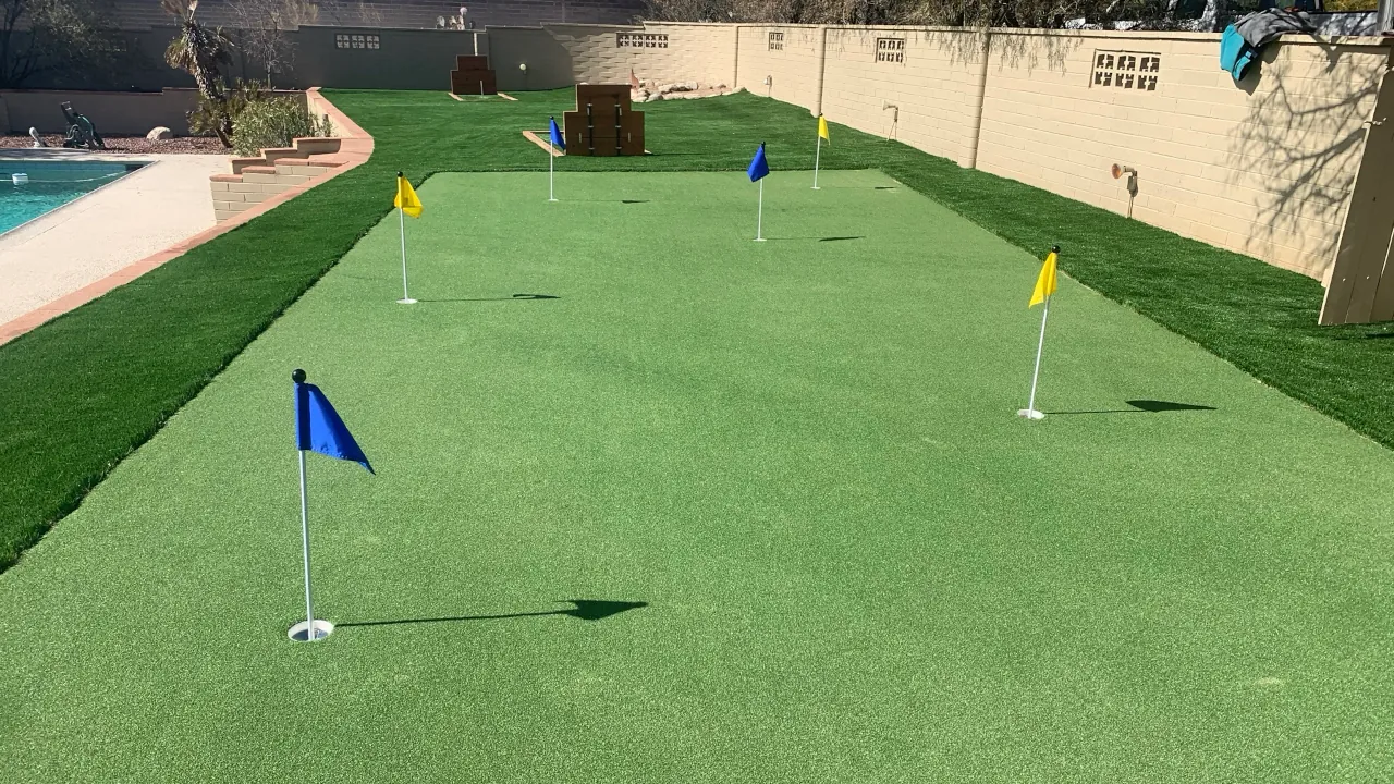 A long, seamless artificial turf surface with multiple practice holes marked by small flags.