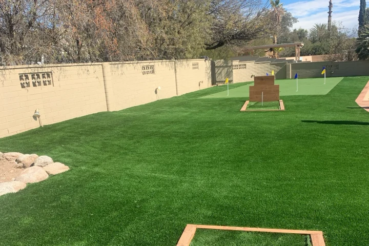 Residential backyard with a newly installed artificial turf putting green and wooden practice targets.