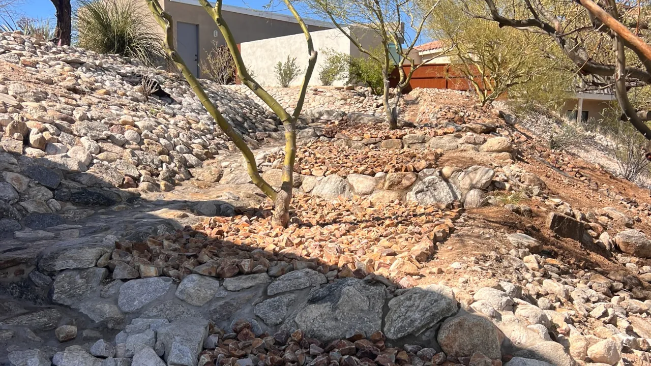 Stacked natural boulders form shallow retaining edges with smaller crushed rock filling the terraces.