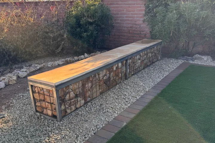 A custom gabion-style bench filled with warm-toned decorative stones on a bed of light pea gravel.