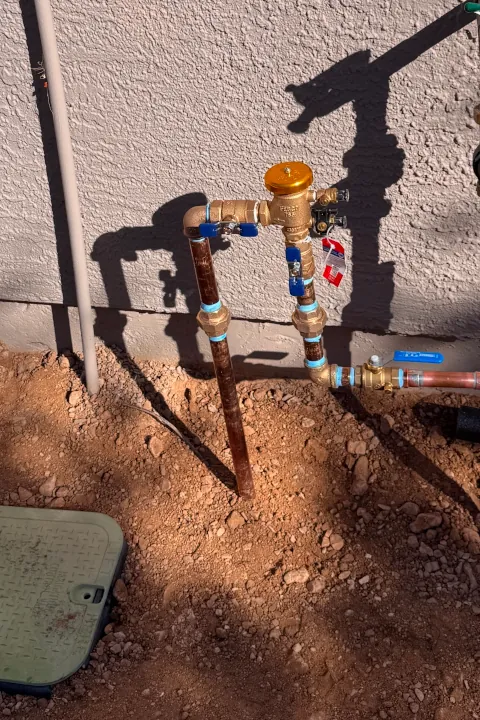Irrigation valve and supply line installed along the side of a residential home.